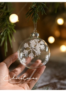 Detailed view of a clear Christmas ornament with white sequins held by hand