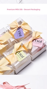 Detail of luxury gift boxes with yellow satin ribbons and clear lids for desserts