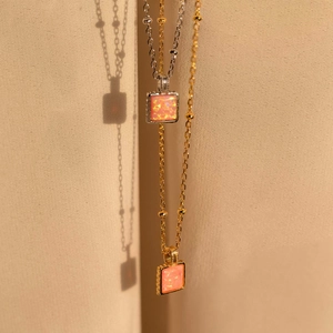 Detail of square opal pendant necklaces in gold and silver finish with pink gemstones