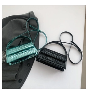 Detailed view of glossy crocodile pattern crossbody bags in vibrant green and black colors