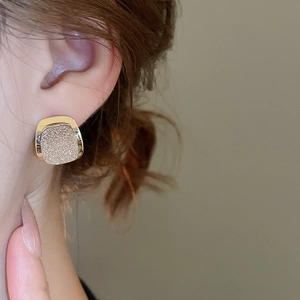 Detail of 18k gold plated square stud earring with sparkling stardust texture on model