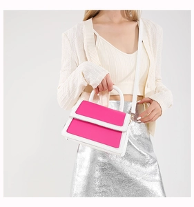 Side view of pink and white contrast handbag styled with a knitted cardigan and skirt
