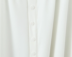 Macro shot of vertical white round buttons and smooth fabric texture on a long dress