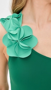 Detailed close-up of 3D layered floral ornament on a one-shoulder green swimsuit