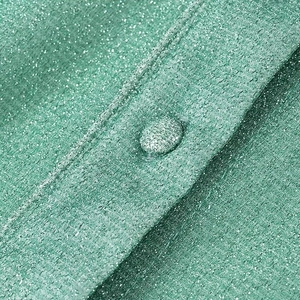 Gros plan sur le tissu vert scintillant et le détail du bouton recouvert du même textile
