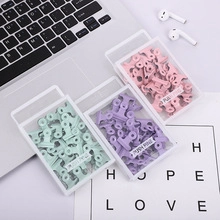 Desktop view of pastel macaron binder clips in pink, purple, and mint green storage boxes