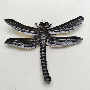 Detail of a black metal dragonfly wall decor showing wing texture and hanging hook on back