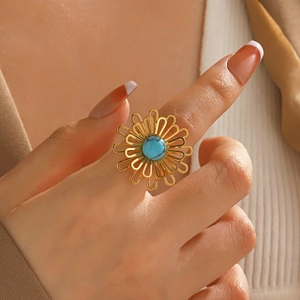 Elegante anello a fiore dorato con intarsio di turchese indossato da una modella
