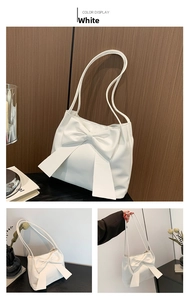 Detailed view of the large white bow decoration and soft faux leather on the tote bag