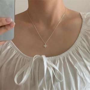 Detail view of a sterling silver cross necklace with pavé zircons worn on the neck