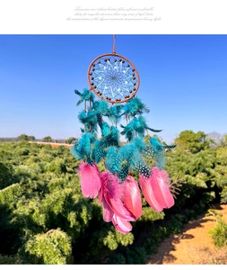 Detail of bohemian dream catcher with vibrant turquoise and pink feathers against blue sky