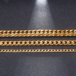 Three widths of polished gold stainless steel Cuban chain necklaces on black texture