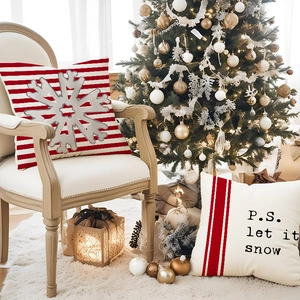 Red Christmas snowflake pillow covers with P.S. let it snow print on an armchair