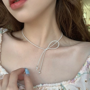 Elegant white beaded choker necklace with a sweet bow design worn by a model