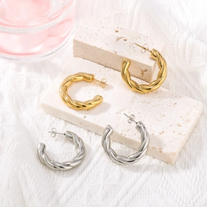 Twisted C-shaped stainless steel earrings in gold and silver finish on stone base