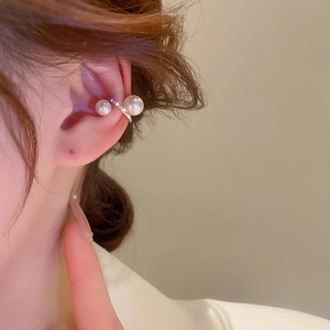Detail of twisted pearl ear cuff with zircon accents worn by model on ear