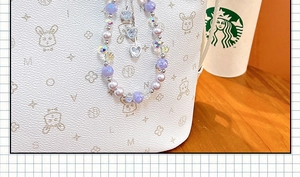 Detailed close-up of an elegant purple beaded charm featuring pearls and heart crystals