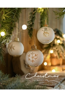 Close-up of 8cm white frosted glass Christmas balls with snowflakes hanging on pine branches