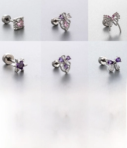Dettaglio macro di borchie in acciaio al titanio argento con zircone farfalla viola e rosa