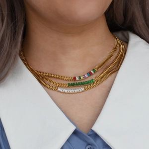 Détail d'un collier doré triple rang avec pierres de zircon colorées, vertes et claires