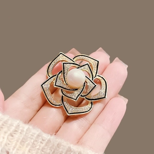 Exquisite gold camellia flower brooch with pearl center and rhinestones on model's hand