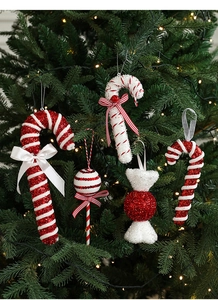 Close-up of glittery red and white candy cane ornaments hanging on a green Christmas tree