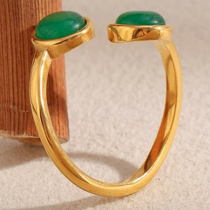 Détail macro d'une bague ouverte en acier doré ornée de deux agates vertes