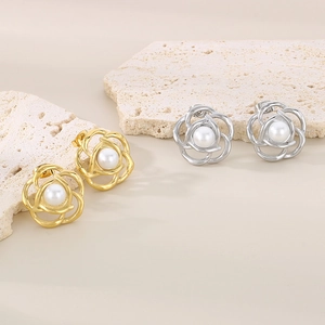 Detail of camellia flower pearl earrings in gold and silver finish on stone base