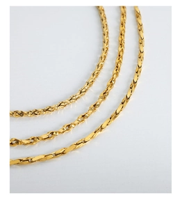 Close-up of geometric twisted flat chain jewelry set with polished golden finish