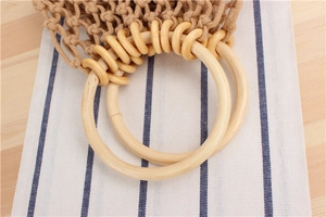 Close-up of hand-woven cotton mesh bag with natural round wooden handles and textured knots
