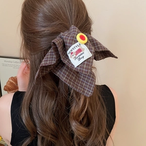 Brown plaid bow hair clip with yellow button detail shown on a ponytail back view