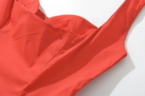 Vue détaillée du décolleté de la robe rouge et des fines bretelles avec coutures