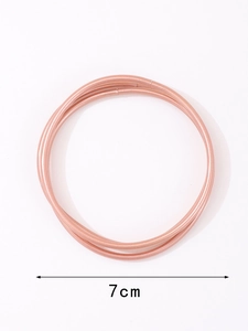 Dettaglio di tre braccialetti rigidi in oro rosa con indicazione del diametro di 7cm