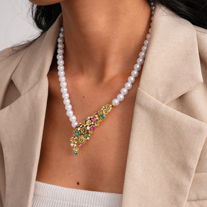 Close-up of vintage flower pendant with pink and emerald crystals on a pearl necklace