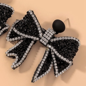 Dettaglio di eleganti orecchini a fiocco nero con strass luccicanti e rifiniture in argento