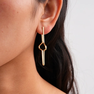 Close-up of golden geometric cross star earrings on model showing shiny metal finish