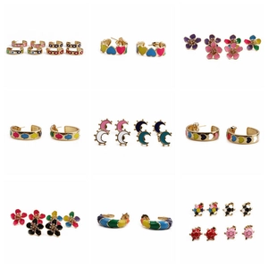 Close-up of gold-plated earrings featuring enamel charms like evil eye, heart and flowers