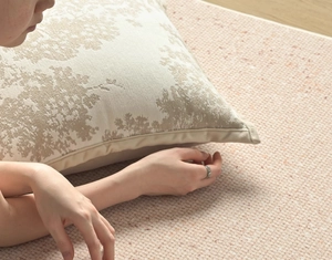 Detailed texture of beige floral cotton linen cushion on a modern textured living room rug