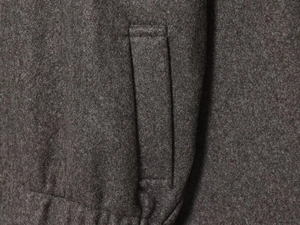 Detailed close-up of dark grey wool blend fabric and precision stitching on jacket pocket