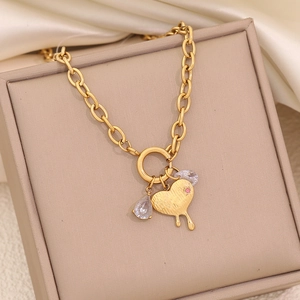 Macro detail of gold heart pendant with pink crystal on a chunky chain in a gift box