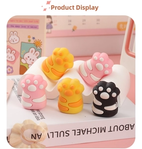 Close-up of cute cat paw erasers in pink, yellow and black on a soft pink desk setup