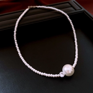 Detailed close-up of a pearl necklace with large focal pearl and sparkling zircon stone