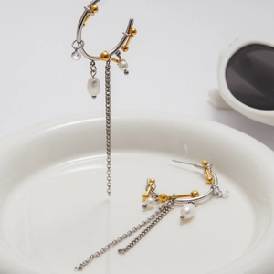 Detail of 18K gold and silver mixed tone C-shape earrings with pearl and metal tassels