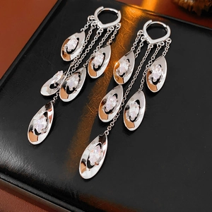 Détail macro de boucles d'oreilles pampilles en argent avec zircon et gouttes en métal