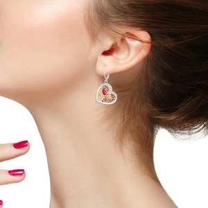 Close-up of heart-shaped earring with red bird and gold flower on female model