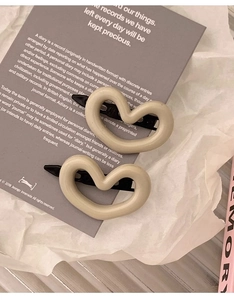 Gros plan de deux pinces à cheveux en résine beige en forme de cœur sur une carte