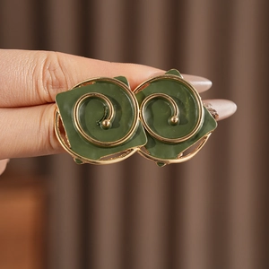 Macro shot of dark green enamel square swirl earrings with gold-tone metal frames
