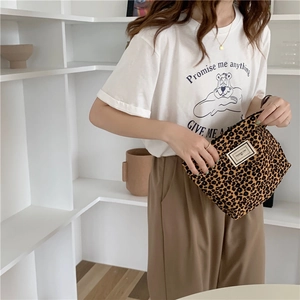 Detail showing high-quality leopard print canvas pouch held by a model in a minimal setting