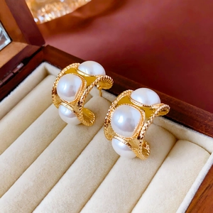 Detail of vintage gold pearl earrings in a wooden jewelry box with soft velvet lining
