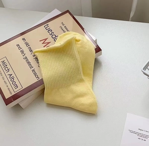 Close-up of yellow knitted cotton striped socks with ribbed cuffs on a white surface
